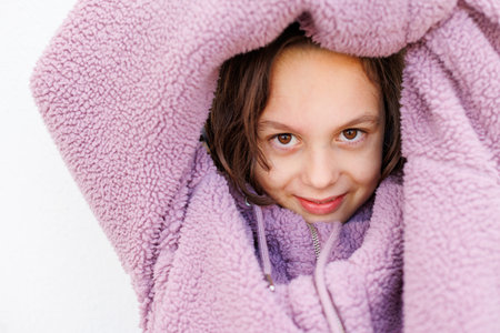 portrait of a boy in a purple sweater with the hood pulled low over his eyes. A child in a warm...