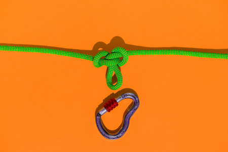 rope with a secure knot and a carabiner lies on a colored background. Equipment for rock climbing and mountaineering. reliable connection. concept of reliability and strength.の写真素材