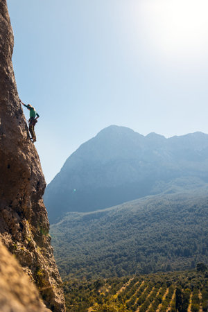 The girl climbs the rocks against the background of the sky and mountains. sports girl is engaged in...