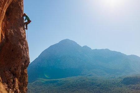 A girl climbs rocks, a rock climber against the backdrop of a mountain, a sporty girl is engaged in rock climbing. extreme sport. Turkey.の写真素材