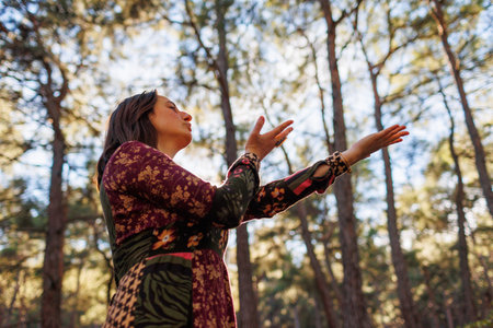 Young beautiful woman dancing in the forest with her hand raised. Concept of balance, harmony and health.の写真素材