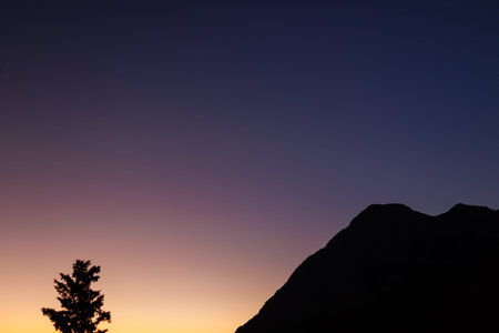 Bright colorful sunset sky over black silhouettes of mountains. Dark sunset sky with bright colors...