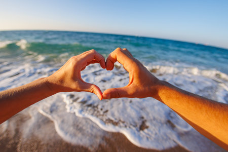happy young couple showing a heart shape with heart-shaped hands on the background of the sea. Concept of love and infatuation.の写真素材