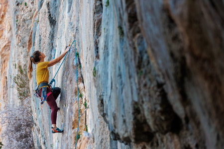 A woman climbs a rock, a strong girl trains strength and endurance, extreme sport, rock climbing on...