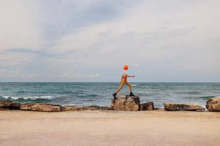 A woman in a futuristic suit jumps over rocks on the beach. Augmented reality game, future...