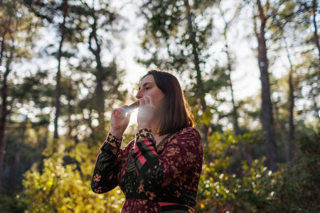 young girl plays the harmonica in the forest. the girl loves to play the harmonica. girl in the...