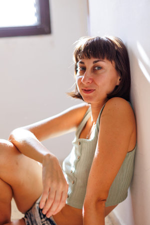 Portrait of a young girl with black short hair in a bright room. Close-up of a carefree young woman....