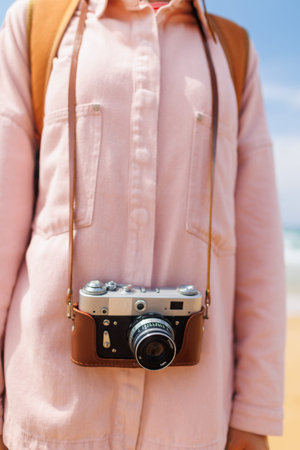 Close-up of a film camera. young girl in a stylish pink shirt and jeans. World Traveler, Travel...