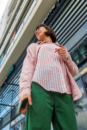 portrait of an elegant woman in stylish clothes with a smartphone on a city street. Happy business...