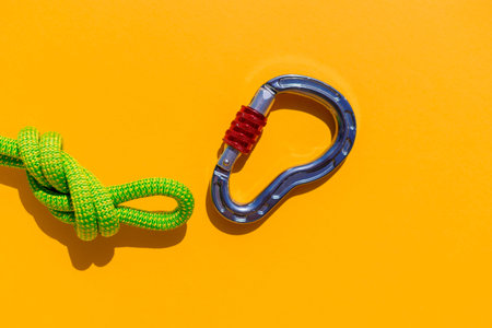 carabiner with a rope lies on a colored background. Equipment for climbing and mountaineering....