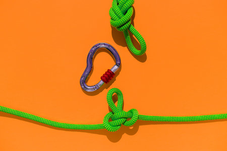 rope with a secure knot and a carabiner lies on a colored background. Equipment for rock climbing...