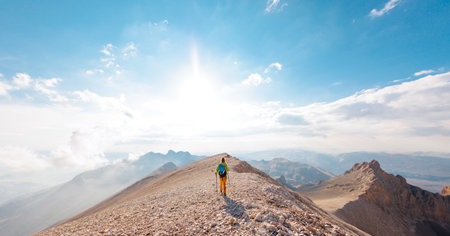 Adventure in the mountains. mountaineering and rock climbing. Hiking in the mountains. A girl with a backpack walks along a mountain path. concept of freedom and adventure. Girl in the mountainsの写真素材