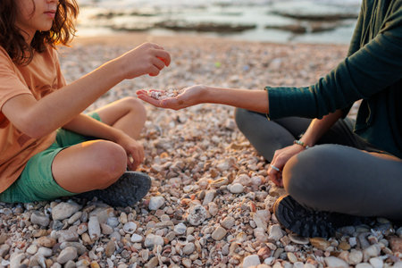 boy collects shells and pebbles in the sea on a sandy beach with his mother. Family having fun on the beach collecting shells. mother and sonの写真素材