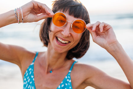 Happy woman smiling and having fun on the beach. Summer portrait of a young beautiful girl. young girl in sunglasses. girl enjoying summer holidays at sea. relaxation on the beach.の写真素材