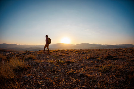 man with a backpack walks along the path against the backdrop of mountains. hiking in the mountains with a backpack. hiking and travel concept.の写真素材