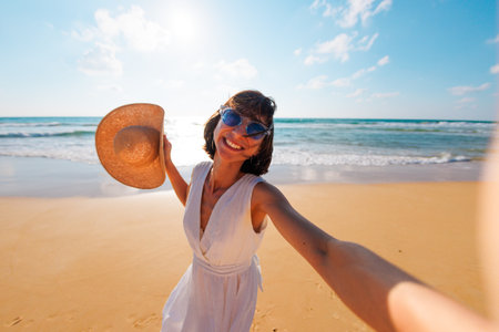 Photo of a young beautiful girl walking on the beach and taking a selfie to the camera. girl takes a selfie.の写真素材