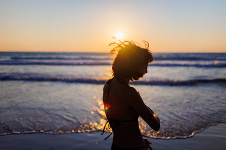 Portrait of a happy girl enjoying summer holidays on the beach. girl walks along the beach at sunset.の写真素材