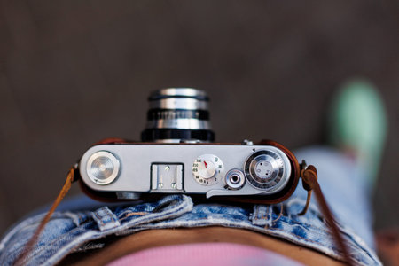 young girl in stylish clothes walks around the city and takes photographs with a film camera....