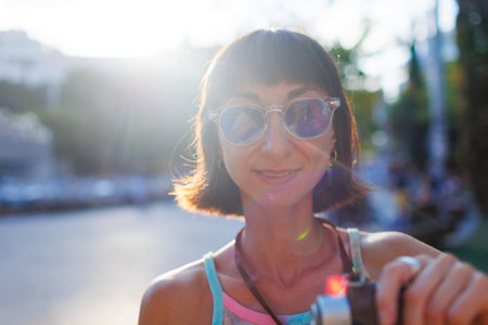 woman photographer with a camera takes pictures outdoors. A young female photographer aims the lens and enjoys the process of shooting.の写真素材