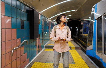 Young girl with a backpack uses a smartphone in the subway. girl waiting for a train. girl in the subway.の写真素材