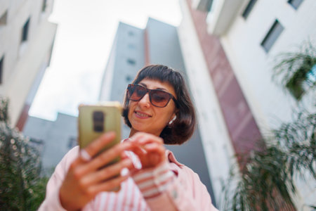 portrait of an elegant woman in stylish clothes with a smartphone on a city street. Happy business woman outdoors. Successful business womanの写真素材
