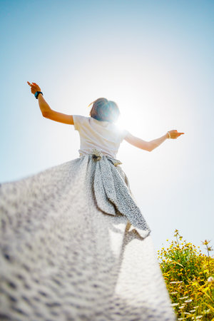 young girl in a flowing white dress. girl in a white flowing dress, rear view, silk fabric fluttering in the wind. a girl in a dress.の写真素材