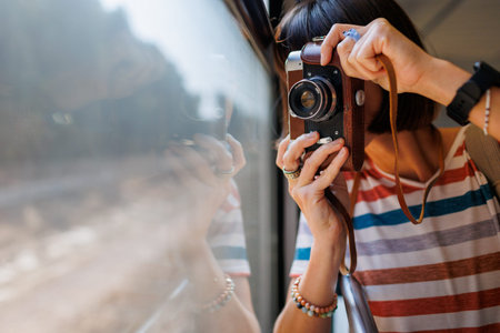 train travel. Young woman enjoying a train ride with a camera. tourist takes pictures of beautiful...