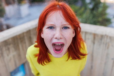 Young girl angry and screaming. Upset girl screaming, teenager with facial piercing.の写真素材