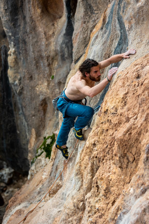 male climber. active recreation in nature. strong muscular male rock climber climbs a vertical rock and makes great efforts to grab hold of the holds. rock climbing in Turkey, Geykbayiriの写真素材