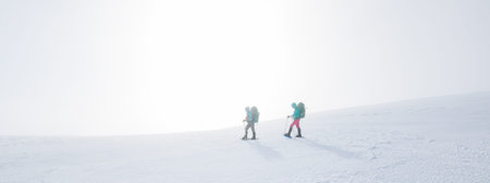 climbers climb the mountain in the snow. Winter mountaineering. two girls in snowshoes walk through...