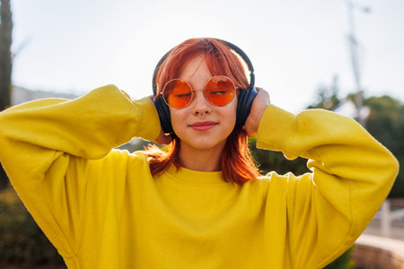 Portrait of a girl with bright hair and facial piercings who uses the phone and listens to music on...