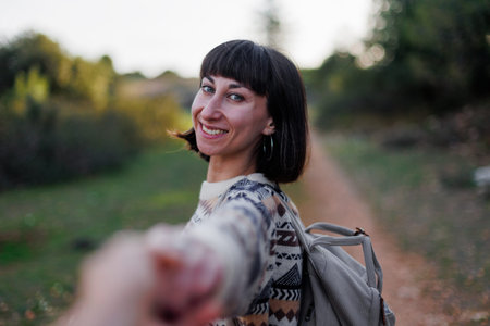 beautiful female traveler with a backpack, standing on the side of a mountain ridge and holding her...