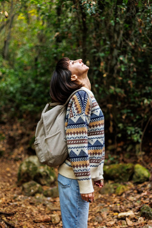 woman in a sweater and a backpack on her back travels. on a hike in the mountains. Adventure and hike. Young happy tourist woman relaxing in natureの写真素材