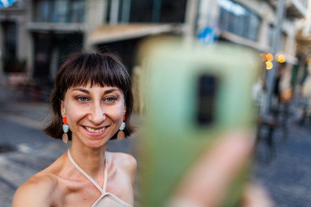 Photo portrait of a girl in casual clothes, smiling, walking along a city street, traveling on holidays and saying selfie. girl takes a selfie.の写真素材