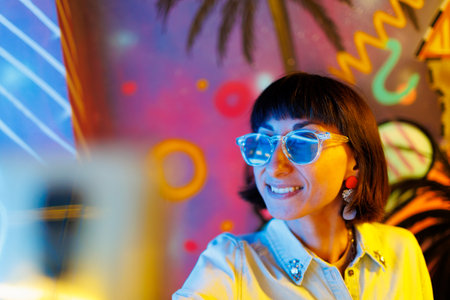 girl at a party. Portrait of a young girl in fashionable glasses taking a selfie using her phone at a party. girl having fun at the party.の写真素材