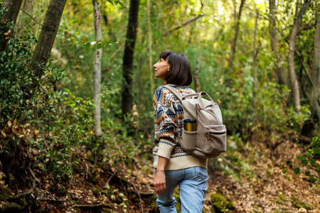 woman in a sweater and a backpack on her back travels. on a hike in the mountains. Adventure and...