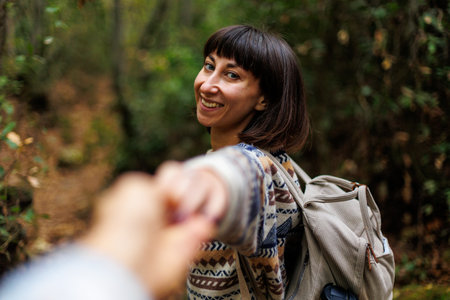 woman in a sweater and a backpack on her back travels. on a hike in the mountains. Adventure and hike. Young happy tourist woman relaxing in natureの写真素材