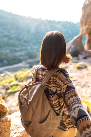 Young woman hiking girl with backpacks. Hiking in nature. Sunny landscape. A young traveler travels along mountain paths. Adventure, travel concept.の写真素材