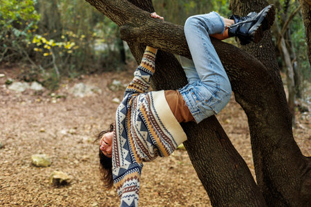 girl having fun in nature. a girl with a backpack hangs on a tree and smiles. hiking and trekking.の写真素材