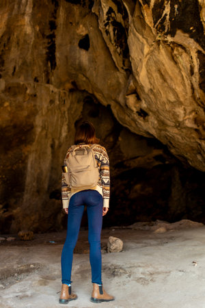 girl with a backpack. A woman with a backpack stands in a cave. The girl explores the cave. Speleologist. Tour of the cave.の写真素材
