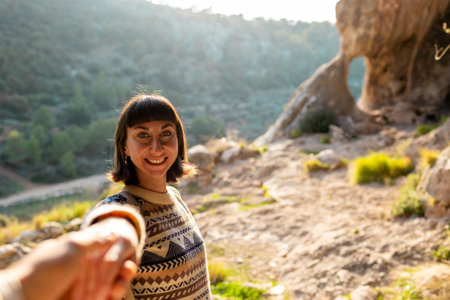 follow me. Portrait of happy female tourist giving hand to her boyfriend. girl smiling. trekking and hiking. Sport and healthy lifestyle concept. girl with backpack.の写真素材