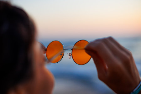 girl near the sea. girl holds sunglasses in her hands. a young girl enjoys her holiday by the sea.の写真素材