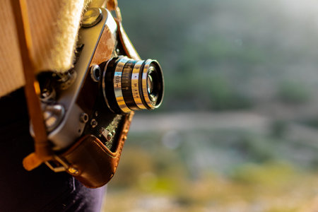 happy woman in the mountains with a camera in her hands. girl relaxing and taking photos in the mountains. trekking and hiking. girl with a camera. film cameraの写真素材