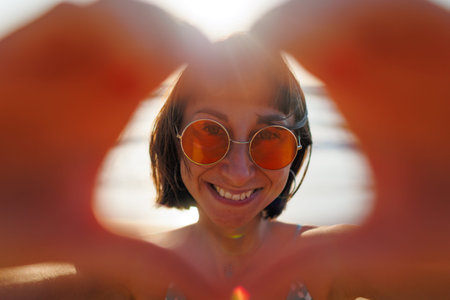 Close-up of a young woman's hands making a heart shape. Portrait of a beautiful woman making a heart...