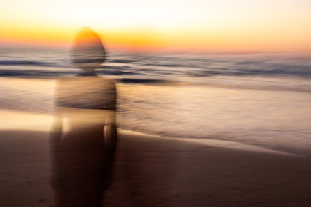 A silhouette on the beach at sunset. Soft focus and long shutter speed create a blurred motion effect. Summer mood.の写真素材