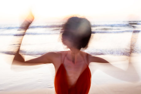 A silhouette at the beach during sunset. Soft focus and long shutter speed create a blurred motion effect. Summer mood.の写真素材