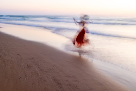 Happy woman walking on the beach. soft focus and long shutter speed. Blurred motion. Summer mood.の写真素材