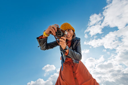 Woman taking photos outdoors. close-up of camera. Young beautiful girl creating content while walking on the beach. travel and vacation.の写真素材