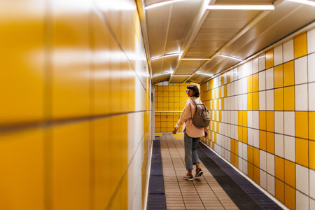 Young woman backpacker traveler walking alone on train station platform with backpack. woman waiting...