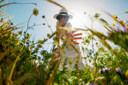 Summer mood. a girl touches flowers while walking through a meadow. A young girl collects flowers in the field. a girl in a dress.の写真素材